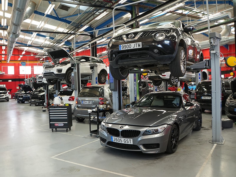 Interior del taller Dasercars con varios vehículos elevados y mecánicos trabajando